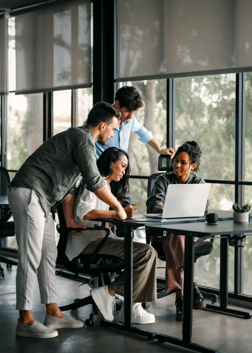A team collaborating around a laptop in a modern office